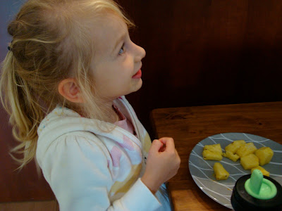 Little girl sitting at table eating snacks