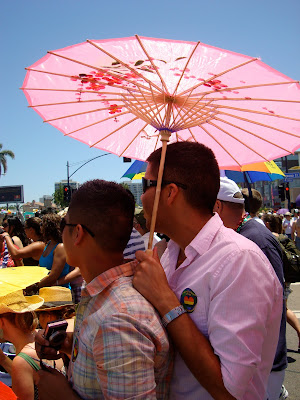 Two men standing under pink parasol