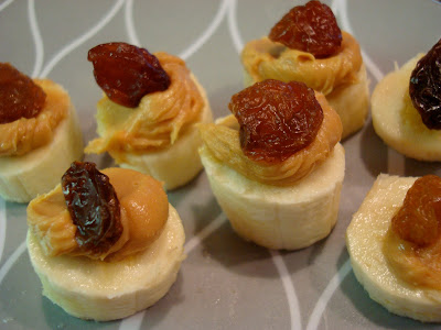 Close up of banana slices topped with peanut butter and raisins