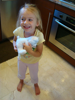 Young girl holding stuffed animal in kitchen