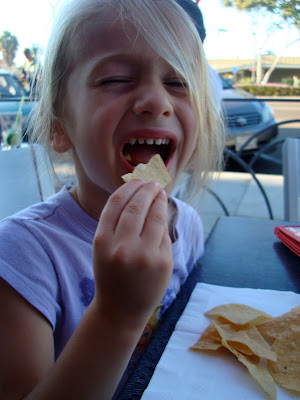 Young girl with mouth open eating chips