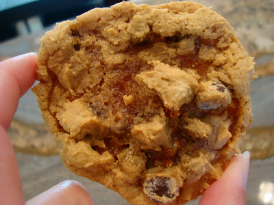 Close up of hand holding one Vegan GF Peanut Butter Caramel Chocolate Chip Cookies with Peanut Flour