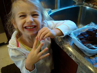 Young girl making silly face with fudge on countertop