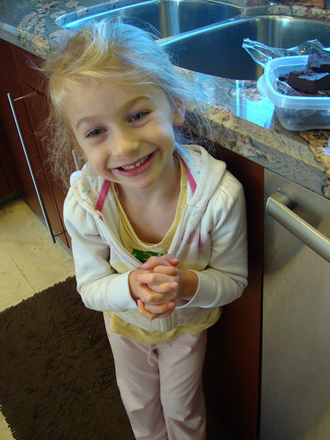 Young girl smiling and clasping hands in kitchen