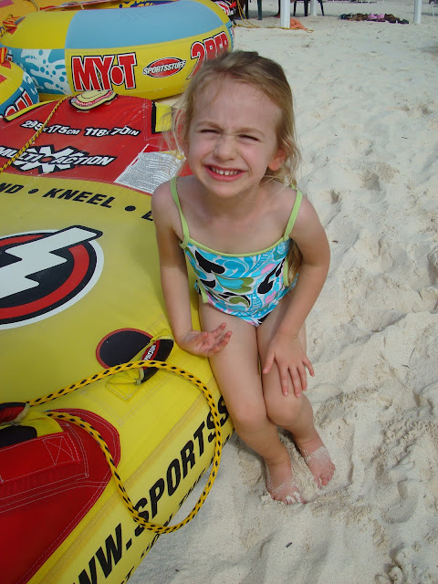 Young girl in bathing suit sitting on large blow up tube