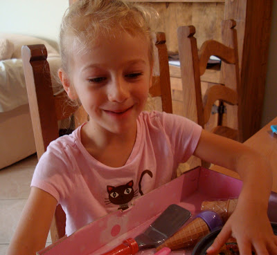 Young girl making excited face while opening up package of gift
