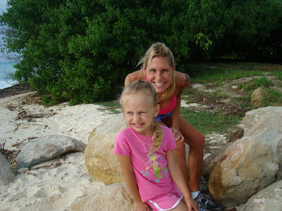 Woman leaning over on rock smiling over young girls shoulder