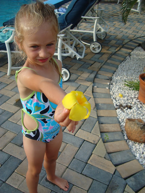 Young girl in swimsuit holding out flower