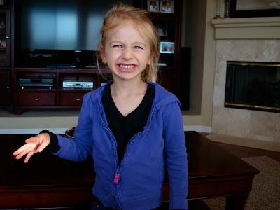 Child standing in front of coffee table with arm out smiling