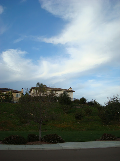House on hill with blue sky with a wisp of clouds