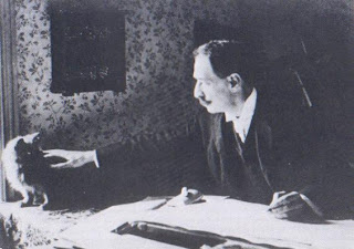 Louis Wain (1860-1939) dibujando con uno de sus gatos en la mesa