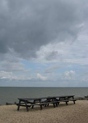 Grey clouds above a pub bench on the beach