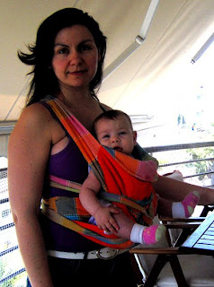 Με το μωρό στο μάρσιπο αγκαλιάς mei tai, να κοιτάζει μπροστά (έξω), με τα πόδια έξω.