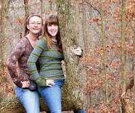 two happy females sitting in a tree outside on the hiking trail.