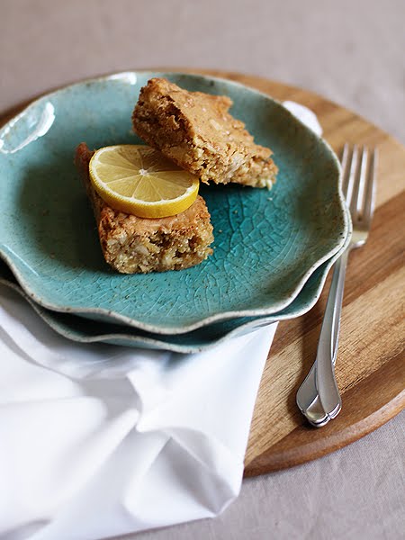 Two white chocolate blondies on a blue plate garnished with a slice of lemon