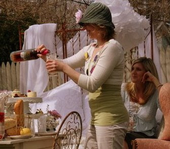 WIman pouring wine into a glass wearing a hat