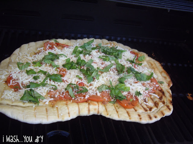 Grilled pizza topped with tomatoes, cheese and spinach. 
