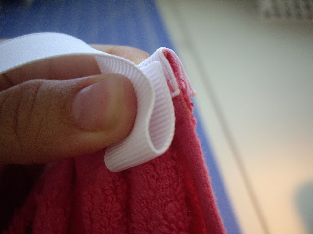 A hand pinching ribbon to fabric.