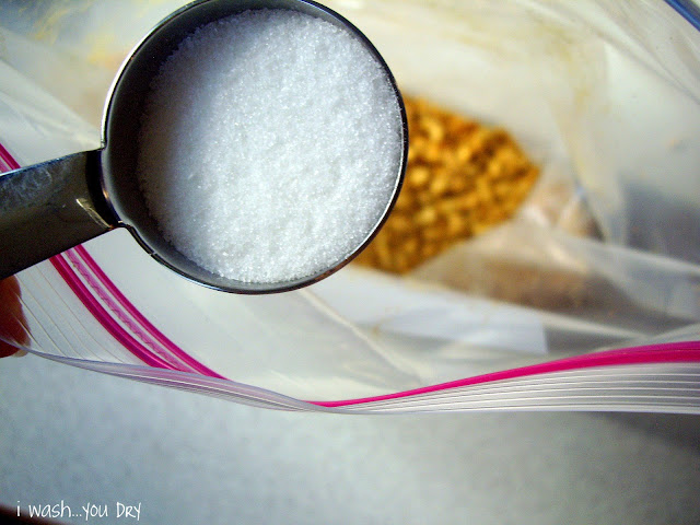 A measuring cup of sugar above an opened ziplock bag with crushed graham crackers in it. 