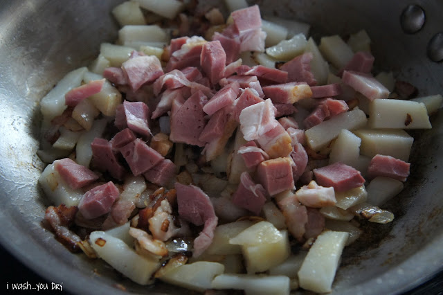 Close up of chopped potatoes and pan cooking in a skillet.