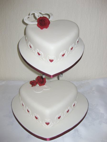 White heart shaped wedding cake with red trimming