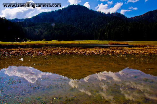 Khajjiar Trip during my Sabbatical - Part 2 : Posted by Vibha Malhotra at www.travellingcamera.com : During my Sabbatical in Feb this year, I went for a solo trip to Dalhousie, Himachal Pradesh on a friend's recommendation. While staying in Delhi, I took a taxi to Khajjiar and reached there early morning, which  was a good thing. The place is a very popular tourist spot and is therefore almost always crowded. In my case, early arrival ensured a stress-free stroll and some amazing pictures.The ground was covered with soft grass and the area was lined with tall deodars lending it an appearance of a bowl. Tourists had only just started arriving. Therefore, there were only a few cars parked. The lake in the center could have been better maintained though.Houses with colorful sloped roofs dotted the scene here and there adding more character to the scene. A close-up of some of the buildings in the area. houses with sloped roofs fascinate me a lot.One of the old houses in a typical 