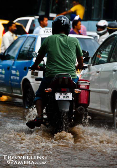 Monsoon Effect in Delhi - 2010: Posted by VJ SHARMA at www.travellingcamera.com : Rains bring joy, rains bring happiness. But along with all this, rain also brings waterlogging and traffic jams in metropoliton cities such as Delhi. But in spite of all that, it is a welcome visitor. And this year, monsoon has been very generous. We had all forgotten what monsoon really means. This year it refreshed all memories...Walking through muddy roads is a challenge, especially when you are wearing flip-flops. And during rainy season, everyone get psyched enough to fold up the trouser legs even when there is no water around. It becomes more like a habit.Some images brought back memories of my childhood.Being splattered with muddy water by a rogue car is a very common tale of misery one comes across during this season of fun and mischief. With several pock-marked roads, driving through the city was a major challenge this season. One advise here is that it is best to avoid water on the sides of the road as you never know what lies beneath that deceptively placid surface.I don't know about other cities but this was a common site in Delhi. Yamuna has been flowing above the danger mark since the last 5 days and the water from the river also spilled over near ISBT.Half an hour worth of rain was enough to cause jams that lasted for hours. The drainage system completely went for a toss.But still, all of us love rains and a dry monsoon means soaring tempers, mounting irritation and silent hopelessness. So God, please give us decent amount of rains year after year. 
