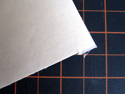 Edge of a piece of white fabric, with threads hanging.