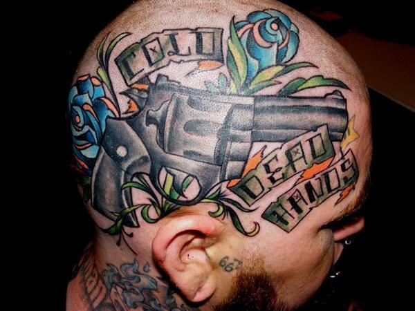 Head tattoo with gun and flowers plus motto