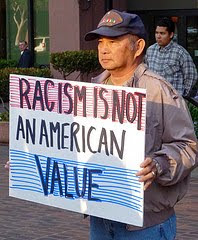 protester with sign that says Racism is not an American value