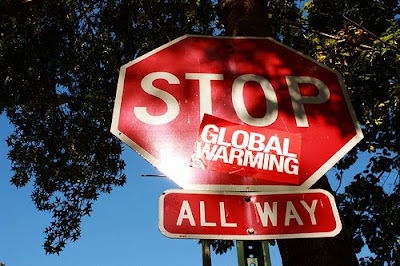 stop sign with sticker that says global warming under stop