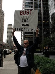 man with sign that says bust the banksters