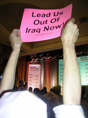 protester holding pink sign that says lead us out of Iraq now