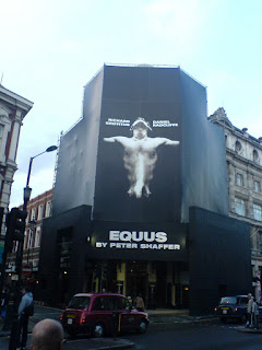 the facade of the Gieguld Theatre hidden by a giant poster for Equus