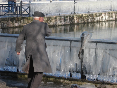 old man throwing stones on frozen lake