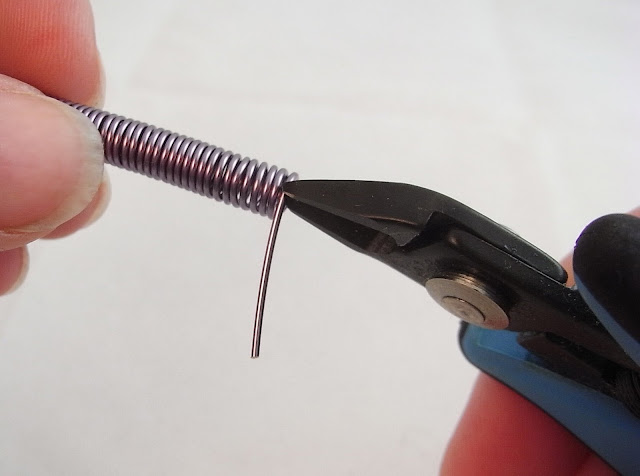 Using flush cutters to trim away the excess wire from the end of the jump ring coil