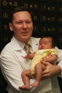 Image: Dr Kenneth Snell holds a baby conceived with the help of his acupuncture and herbal fertility treatment