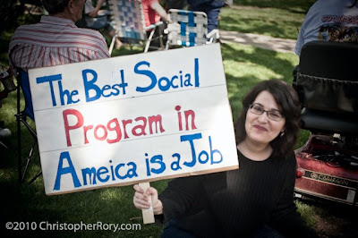 Smiling white woman with sign reading The best social program in Ameica is a job