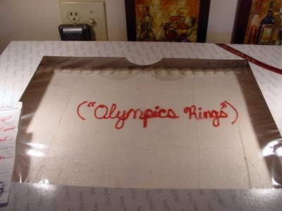 White cake with red letters that say quote Olympic rings unquote