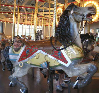 Carousel horse with a face in bas relief off the end of its saddle