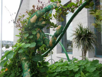 A green sculptural figure covered with plants