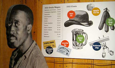 Black and white cutout photo of a black man looking into the camera, next to a sign showing images and prices