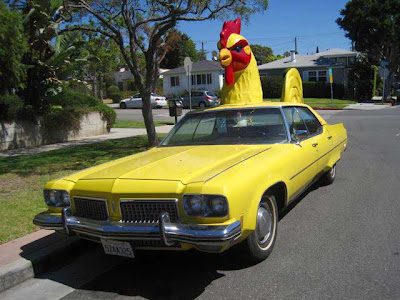 Yellow Cadillac with a yellow and red rooster atop it