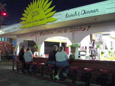 Outdoor lunch counter with handmade sign above that reads Absolutely nothing on a stick