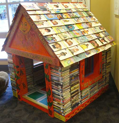 Miniature house made out of stacked books, with books for shingles on the roof
