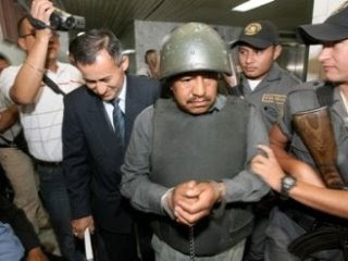 Abraham Lancerio Gomez in helmet and handcuffs, in a crowd