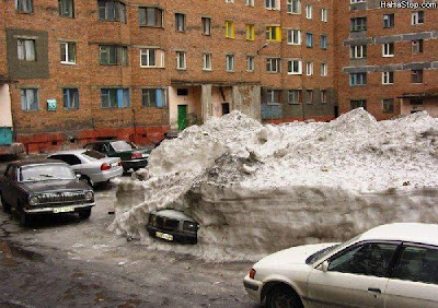 photo of a car buried in a huge pile of snow