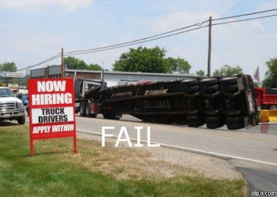 photo of a truck laying on its side, by a truck driver wanted sign