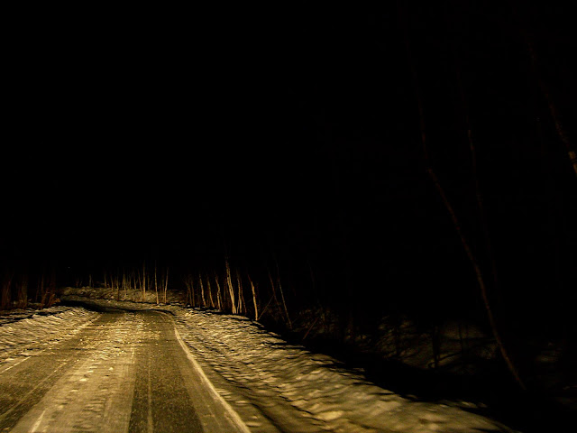 Icy New Hampshire road at night, illuminated by headlights.