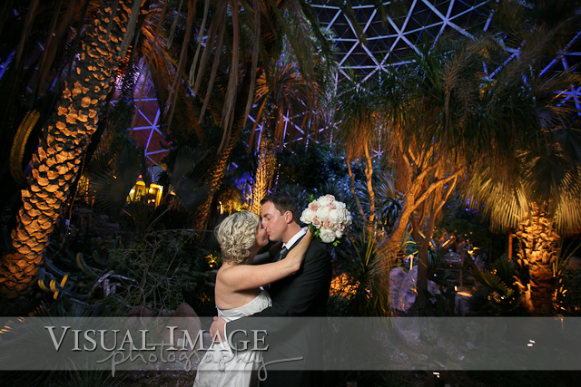 Bride and groom kissing in arid dome during wedding at Mitchell Park Domes